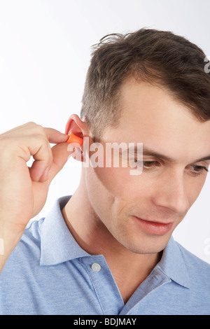 Uomo che indossa i tappi per le orecchie Foto Stock