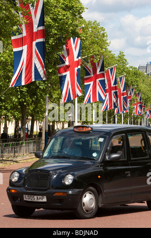 Fila di Unione Jack bandiere lungo il Mall, a Londra come black cab passa al di sotto. Foto Stock