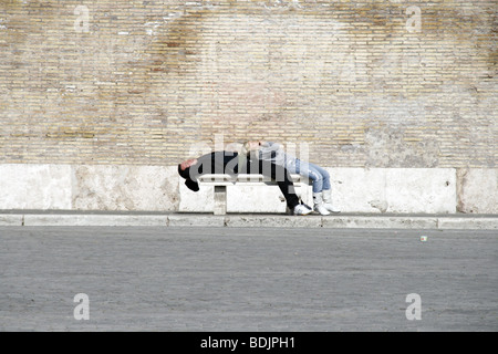 Coppia giacendo su un banco in piazza del Popolo a Roma Foto Stock