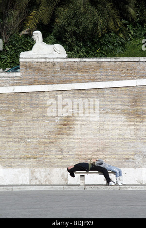 Coppia giacendo su un banco in piazza del Popolo a Roma Foto Stock