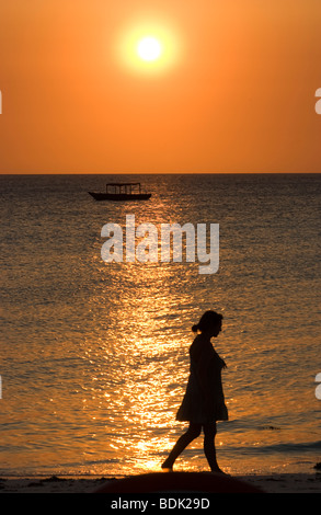 Signora giovane di camminare sulla spiaggia al tramonto Foto Stock