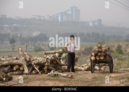 DATONG, nella provincia di Shanxi, Cina - Agosto 2007: Un uomo prende una pausa dal carico albero di taglio si connette al proprio carrello. Foto Stock