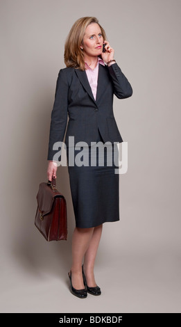 La donna che porta una valigetta e utilizzando un telefono cellulare Foto Stock