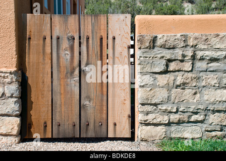 Un rustico cancello in legno si siede in un adobe muro di pietra presso la storica vecchia schoolhouse a Lincoln, Nuovo Messico. Foto Stock