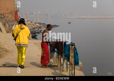 Un Sadhu passeggiate lungo il corso del fiume nella città di Varanasi (Benares). I Sadhu detiene un tridente, l'altro uomo indossa un dhoti. Foto Stock