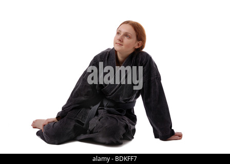 Nudi ragazza in uniforme nera si siede sul pavimento, isolato su bianco Foto Stock