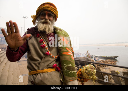 Un Sadhu si erge di fronte al Marnikarnika Ghat (uno di bruciare ghats) nella città indiana di Varanasi (Benares), India. Foto Stock