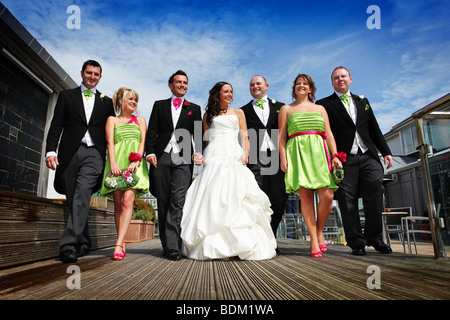 Sposa e lo sposo e la sposa spose cameriere uscieri miglior uomo a camminare mano nella mano a una colorata estate wedding angolazione inusuale Foto Stock