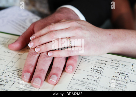 Primo piano della sposa e lo sposo le mani sul registro di matrimonio durante la cerimonia di firma sul giorno di nozze REGNO UNITO Foto Stock