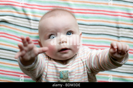 Un bambino alza le braccia a sua madre per essere prelevati. Foto Stock