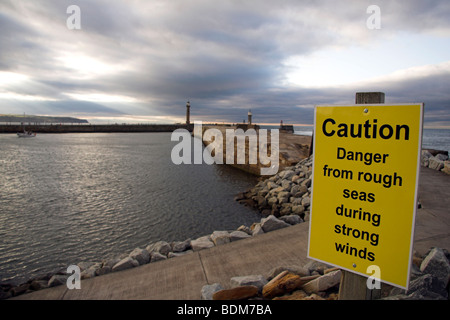 Avviso di attenzione, pericolo dal mare mosso durante i forti venti, Whitby Harbour, North Yorkshire, Inghilterra, Regno Unito Foto Stock