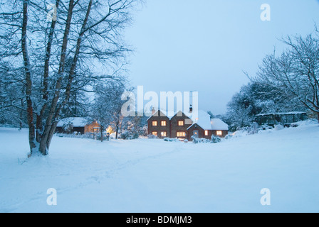 Scheda di Natale Immagine del paesaggio invernale con cosy cottage in Vergine neve con argento betulla la sera prima del buio Foto Stock