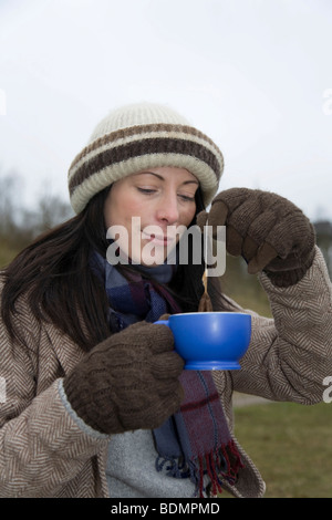 Giovane donna, 30-35 anni, su di un panno umido giorno d'inverno il riscaldamento se stessa con una tazza di tè, Rendsburg, Schleswig-Holstein, Germania, Euro Foto Stock