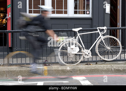 Un velocizzando il ciclista bypassa il ghost bike di Anthony 'Smudge' Smith sulla a Hackney. Foto Stock