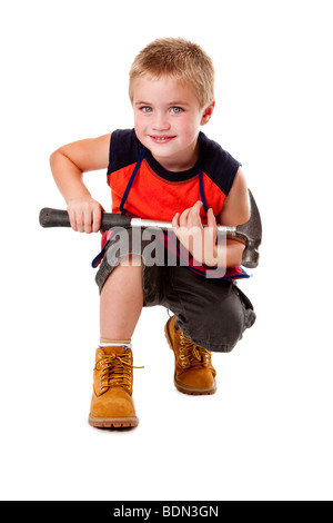 Carino ragazzo giovane azienda per impieghi pesanti martello sul suo giro mentre squatting, isolata. Foto Stock