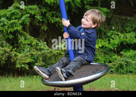 Little Boy, 2 anni, seduto su una giostra, Germania Foto Stock