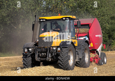 Il trattore e la rotopressa di paglia lavorando in un campo Foto Stock