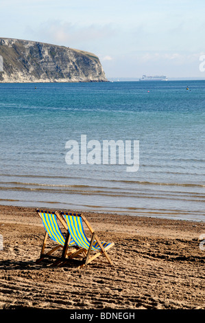 Una coppia di sedie a sdraio guardare fuori alla vista dalla spiaggia a Swanage nel Dorset sulla costa sud dell'Inghilterra. Foto Stock