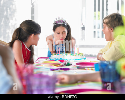 La ragazza (10-12) che spegne le candeline sulla torta del compleanno a parte Foto Stock