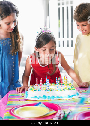 La ragazza (8-12) che spegne le candeline sulla torta del compleanno Foto Stock