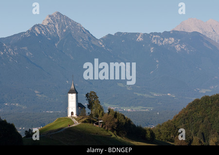 La chiesa di Saint Primoz (Primus) a Jamnik, Slovenia, contro il suggestivo sfondo del monte Storzic. Foto Stock