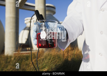 Scienziato sperimentando con un campione di acqua Foto Stock