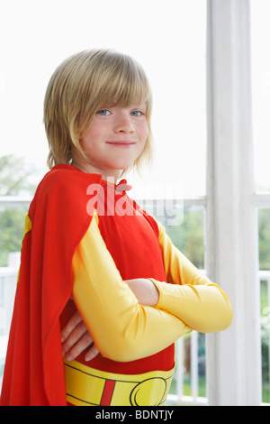 Ritratto di ragazzo (7-9) con le braccia incrociate indossando il costume del supereroe, sorridente Foto Stock