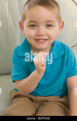 Ragazzo firma la lettera 'T' in American Sign Language Foto Stock