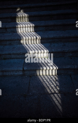 L ombra di una griglia della finestra sui gradini di pietra, Caceres, Spagna Foto Stock