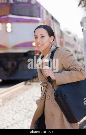 Donna ispanica sta in piedi in una stazione ferroviaria Foto Stock