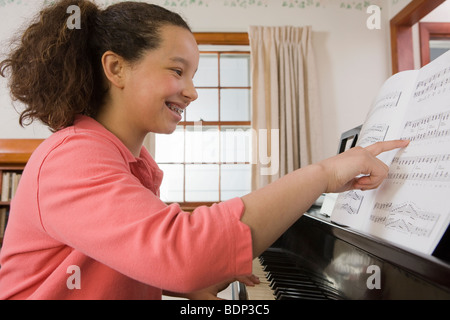 Lettura della ragazza di un foglio di musica su un pianoforte Foto Stock