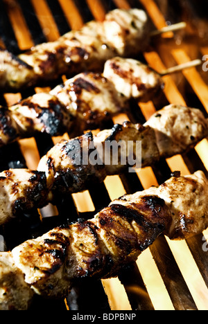 La carne su spiedini essendo cotti alla fiamma su un barbecue. Foto Stock