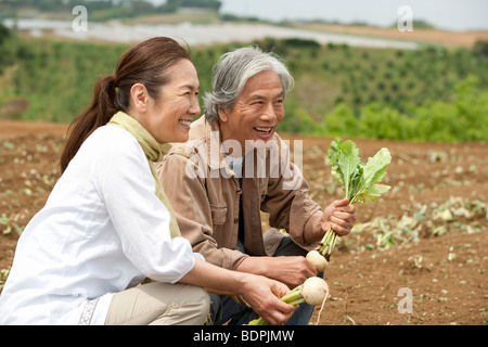 Coppia senior accovacciata sul campo Foto Stock