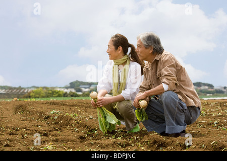 Coppia senior accovacciata sul campo Foto Stock