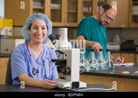 Femmina tecnico di laboratorio sorridente con un chirurgo in background Foto Stock