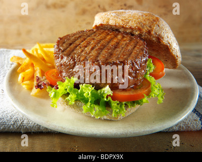 Hamburger di manzo in un panino integrale con insalata e patatine fritte Foto Stock