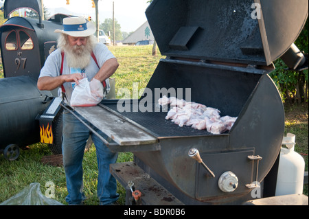 L'uomo grigliare pollo ad un festival estivo annuale in Montagna Nera, NC Foto Stock