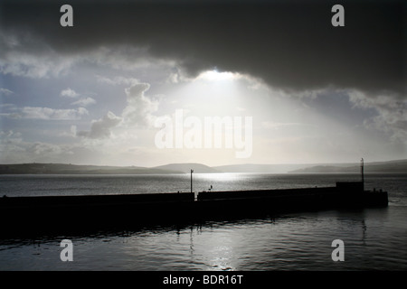 Rompere la tempesta, la luce del sole attraverso lo streaming di nuvole scure su Cornish estuario a Padstow Harbour Foto Stock