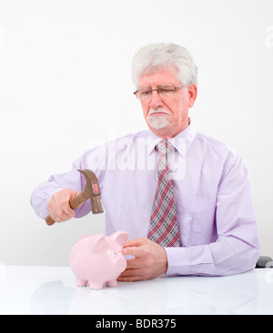 Senior uomo con un martello la rottura di un salvadanaio su bianco Foto Stock