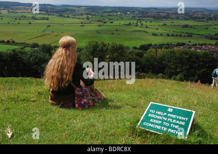 Vista su campi dalla parte superiore di Glastonbury Tor Somerset in Inghilterra con la signora meditando sui prati Foto Stock