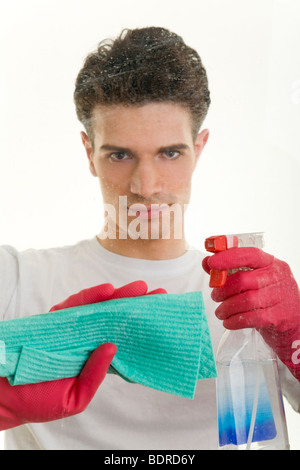Junger Mann putzt mit eine Fensterscheibe mit Spr hflasche und Wischlappen Foto Stock