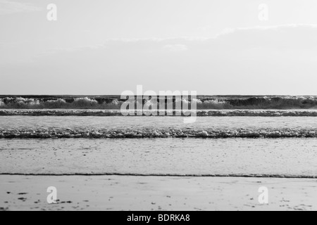 Di medie dimensioni onde infrangersi sulla spiaggia durante il tramonto. Foto Stock