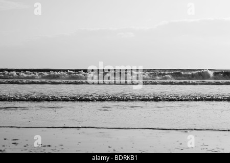 Di medie dimensioni onde infrangersi sulla spiaggia durante il tramonto. Foto Stock