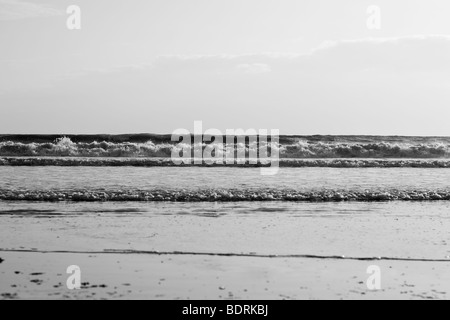 Di medie dimensioni onde infrangersi sulla spiaggia durante il tramonto. Foto Stock