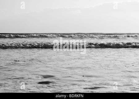 Di medie dimensioni onde infrangersi sulla spiaggia durante il tramonto. Foto Stock