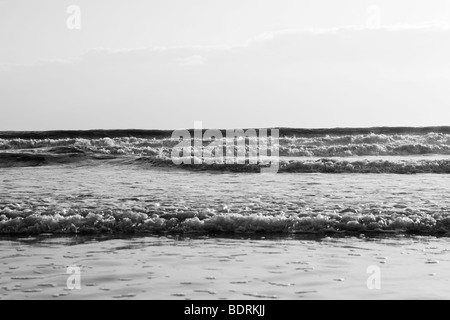 Di medie dimensioni onde infrangersi sulla spiaggia durante il tramonto. Foto Stock