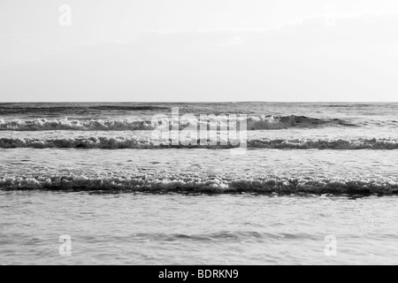 Di medie dimensioni onde infrangersi sulla spiaggia durante il tramonto. Foto Stock