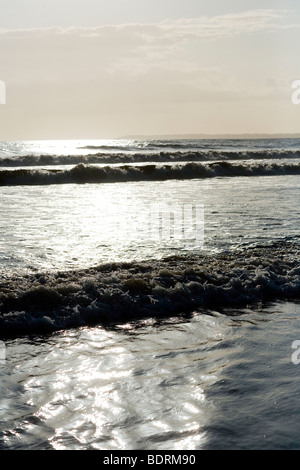 Di medie dimensioni onde infrangersi sulla spiaggia durante il tramonto. Foto Stock