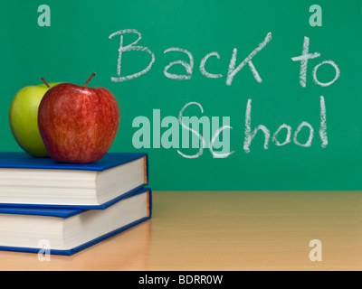 Si torna a scuola scritto su una lavagna. Due mele su libri in primo piano. Foto Stock