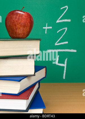 Un aggiunta sulla lavagna con un Apple sulla sommità di una pila di libri. Foto Stock